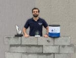 Representante da Ibratin com troféus de premiação, blocos sustentáveis e embalagem da Textura Biotex, simbolizando inovação e economia circular no setor de tintas.