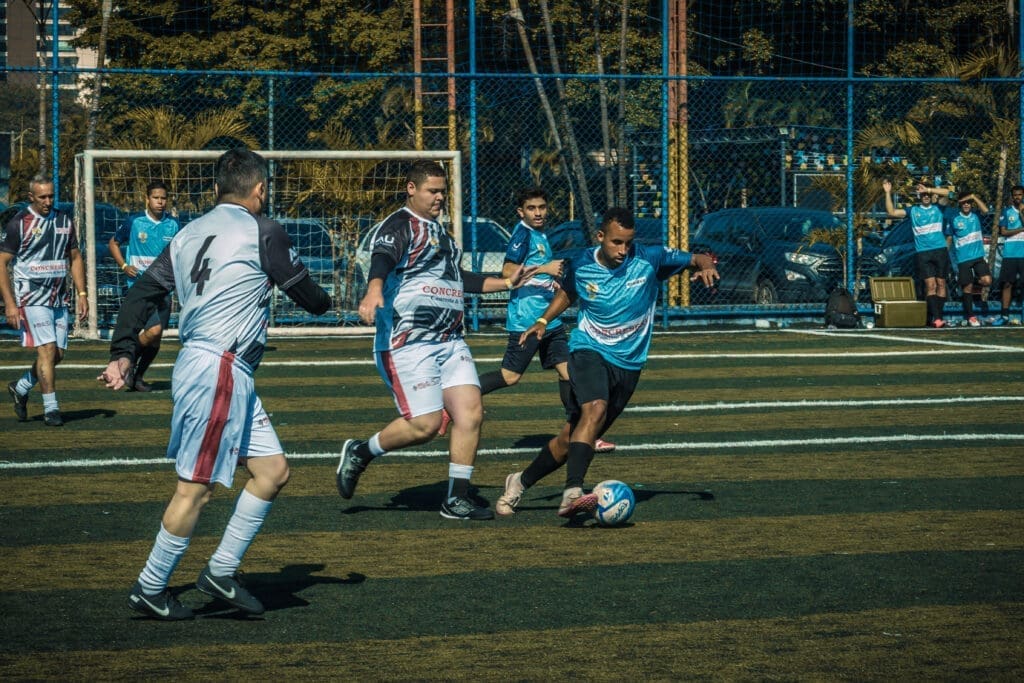 Jogadores disputam lance acirrado durante partida do Torneio Integração da Copa C3 2026, com atletas das equipes em ação no campo de futebol society.