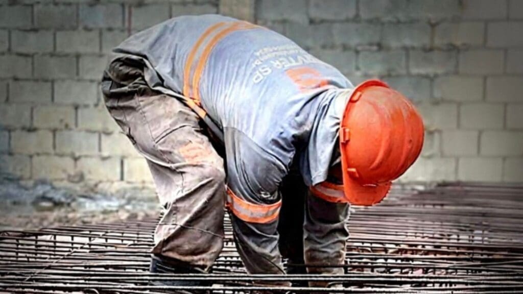 Profissional da construção civil da Servter SP com capacete laranja, realizando montagem de armação de aço em obra.