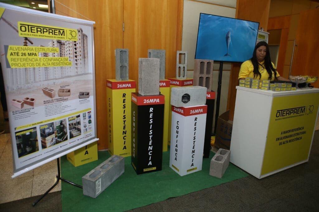 Mini estande de ativação da Oterprem com exposição de blocos de concreto de alta resistência e materiais promocionais durante o Seminário de Alvenaria Estrutural.