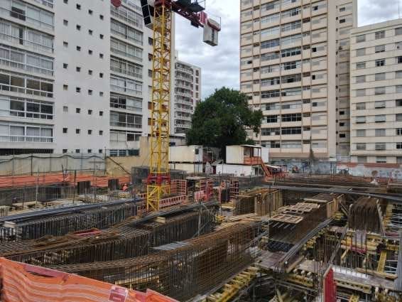 Canteiro de obras com montagem de vigas estruturais pré-armadas em área urbana, destacando a atuação da Aços Urano em projeto de alta complexidade.