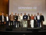 Grupo de palestrantes e organizadores do Seminário de Alvenaria Estrutural do C3 posam juntos no palco do auditório, com o telão ao fundo exibindo o nome do evento.