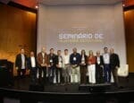 Grupo de palestrantes e painelistas do Seminário de Alvenaria Estrutural do C3 - O Clube da Construção Civil, posando juntos no palco do auditório, com o telão ao fundo exibindo o nome do evento.