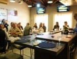 Profissionais da construção civil participam de momento de integração e networking durante o 66° Almoço de Negócios do C3, em ambiente moderno, com mesas redondas e apresentação ao vivo.